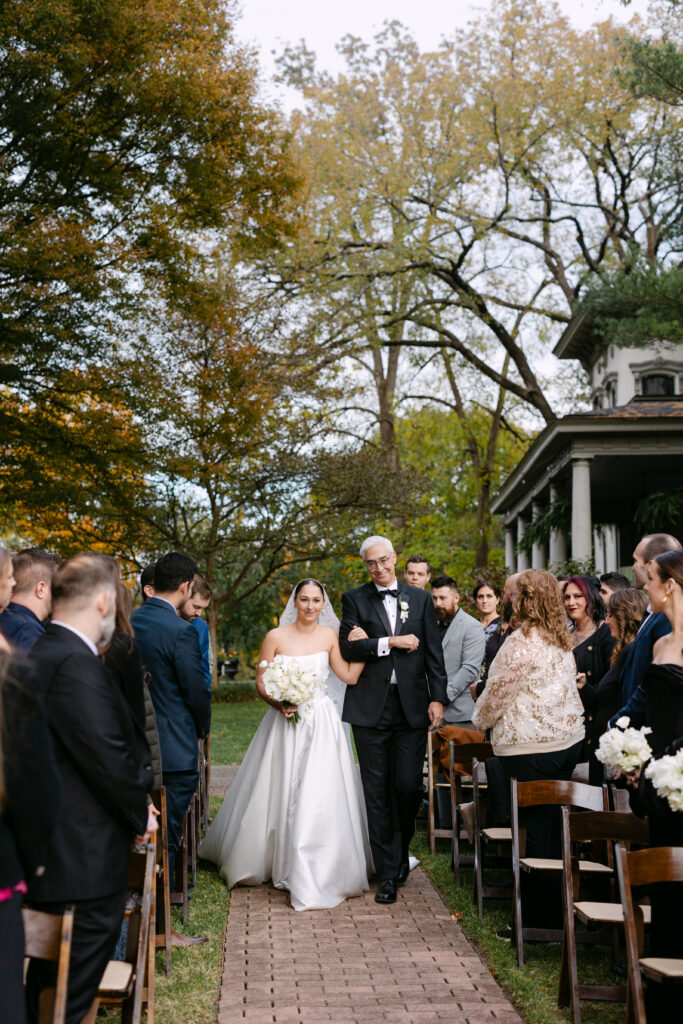Father walking bride down the aisle during garden ceremony at Peterson Dumesnil House