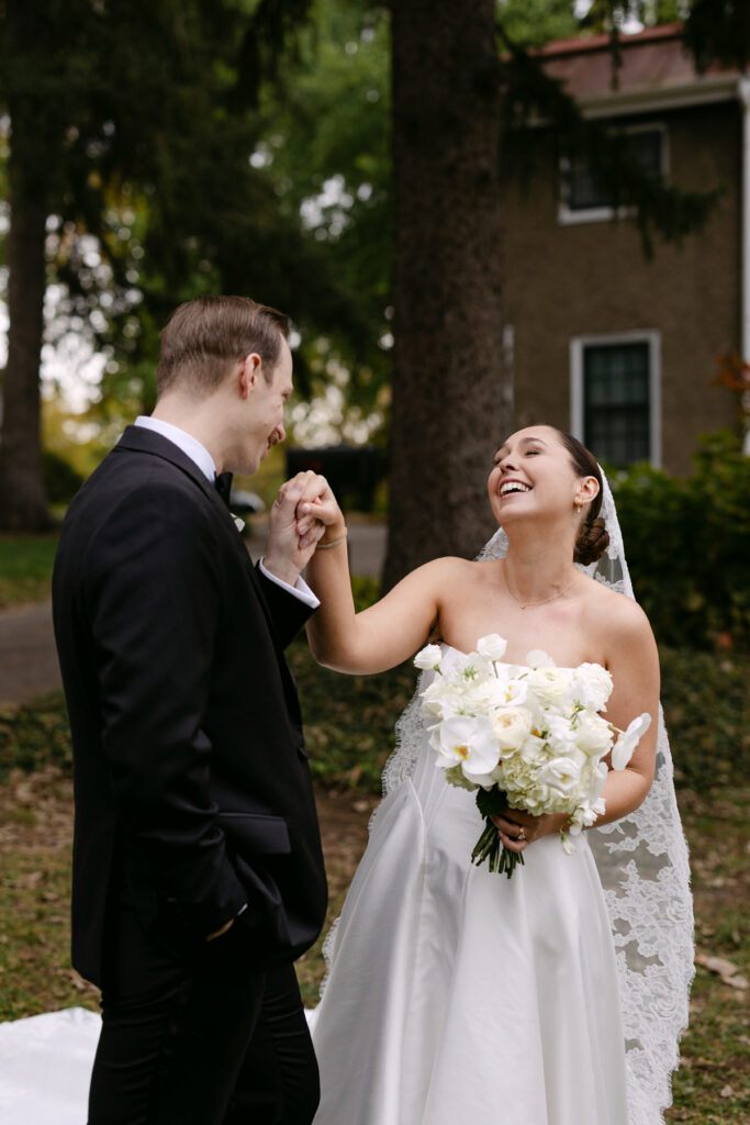 Groom kissing bride’s hand during romantic portrait at Peterson Dumesnil House Louisville wedding