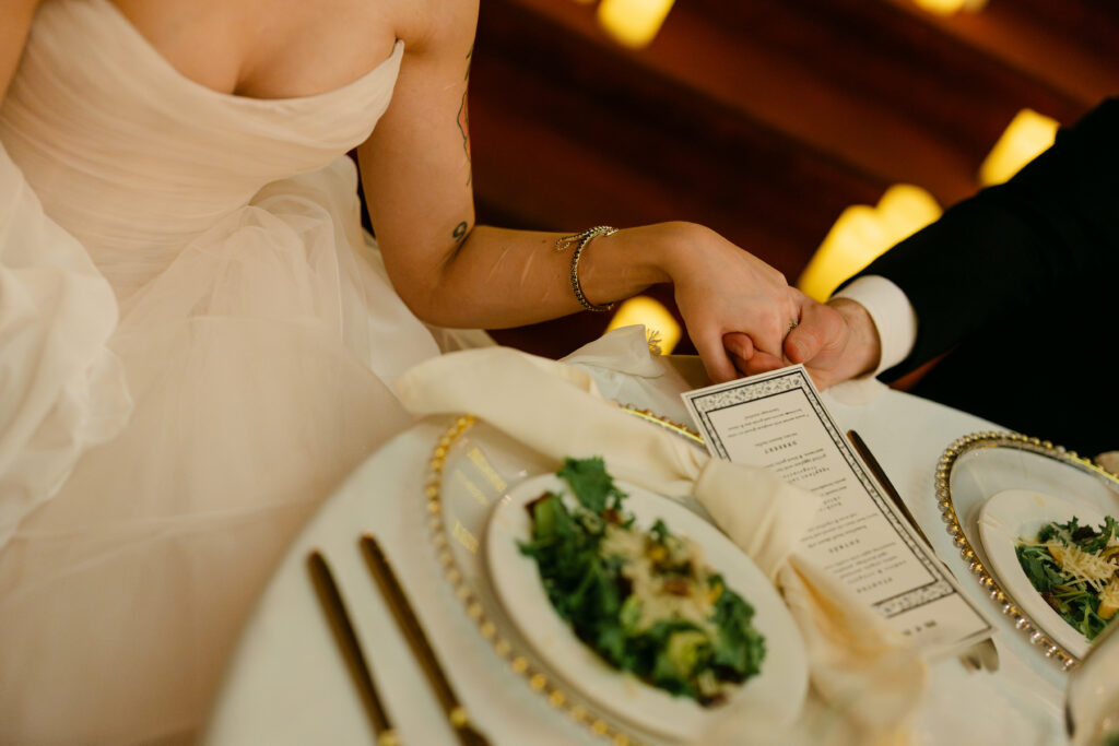 Bride and groom holding hands during emotional wedding speeches at the Louisville Palace in Louisville KY
