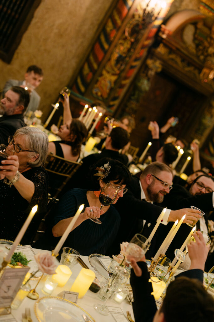 Wedding guests cheering with drinks during a lively Louisville Palace reception in downtown Louisville Kentucky